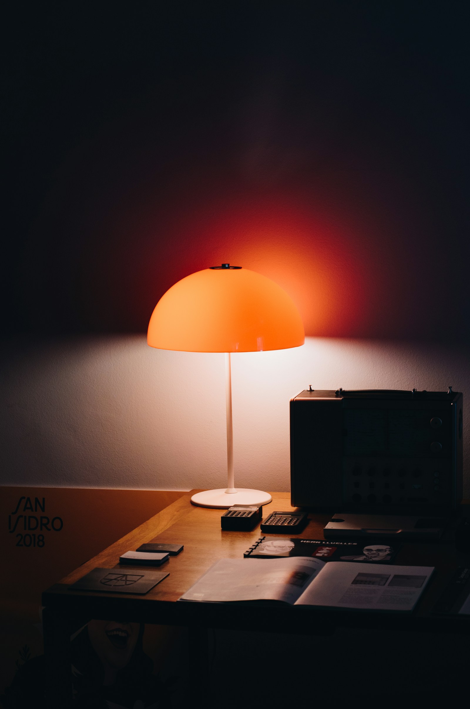 Warmly lit desk with an orange lamp, notebook and tools for focused creative work